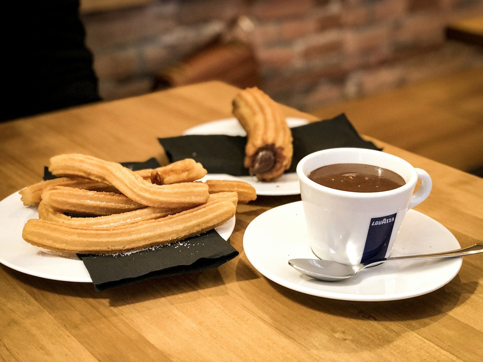 talerz churros obok filiżanki gęstej czekolady do maczania